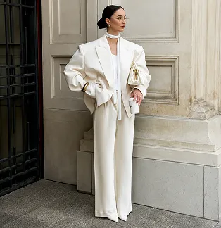 A client in an oversized white suit at the door of a building
