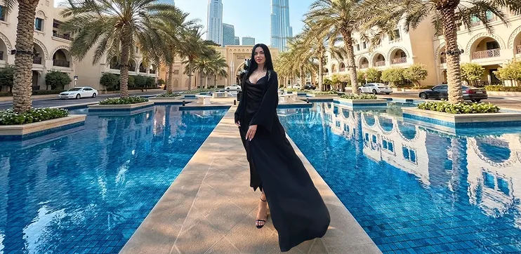 Iryna Ribeiro in a long black dress by a hotel pool in Dubai