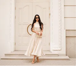 Iryna Ribeiro in a cream midi dress at the entrance of a townhouse