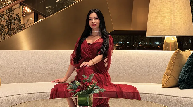 Iryna Ribeiro in a burgundy dress on a sofa in a hotel lobby