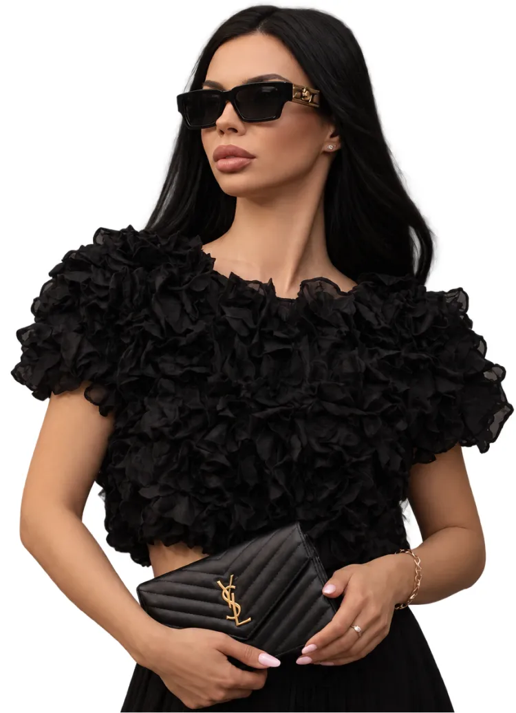 Iryna Ribeiro in a black ruffled top holding a black clutch