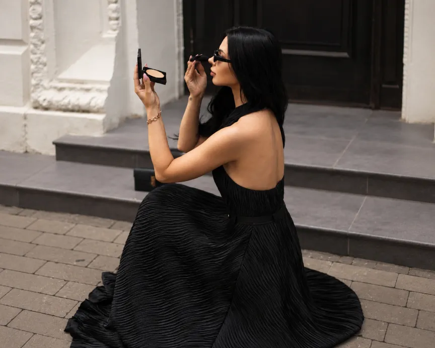 A woman in a long black dress on the steps of a building