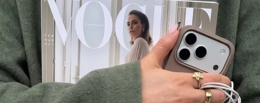 A hand with a phone over a fashion magazine