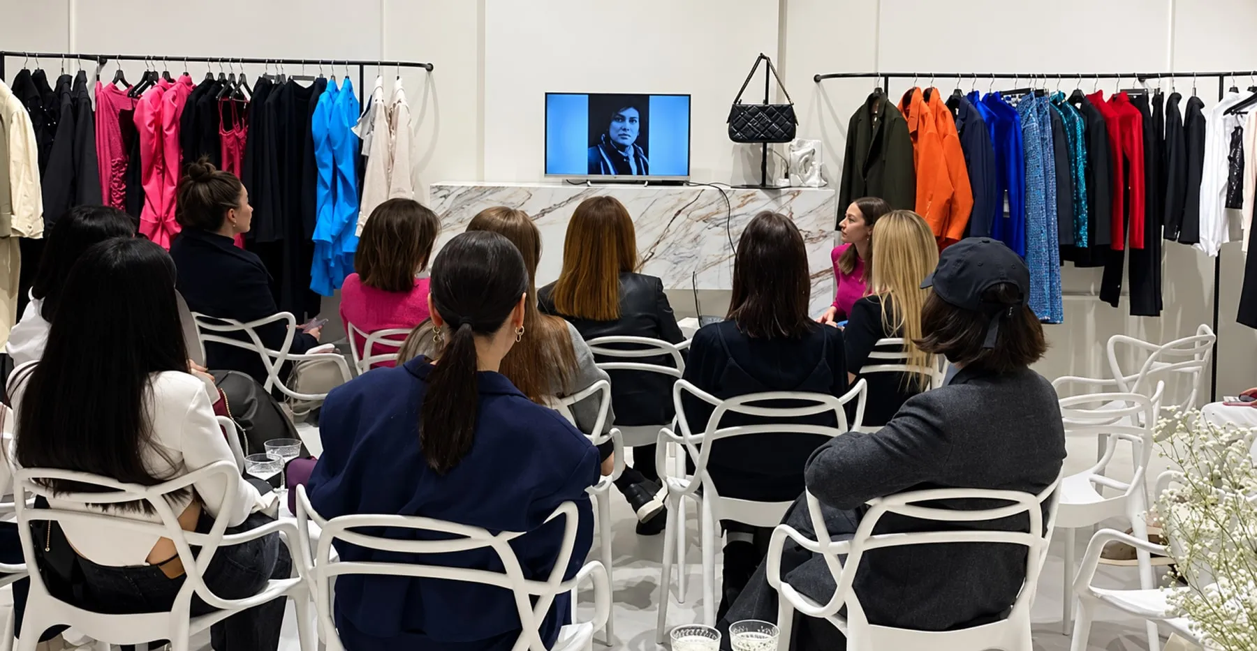 Guests at a styling masterclass in a store, in front of rails of clothes