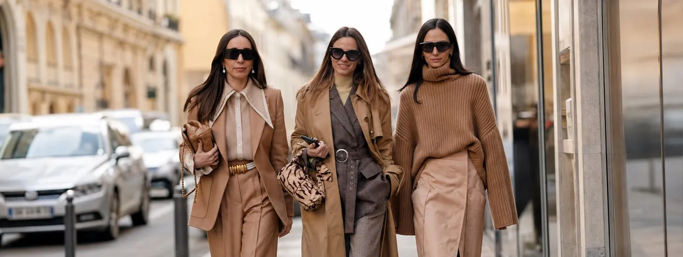 Three women in beige outfits on a city street