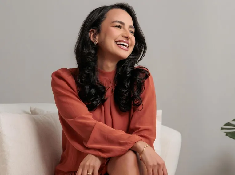 A smiling client in a terracotta dress sitting on a sofa