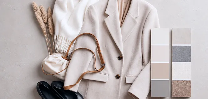 A beige coat, scarf, bag and shoes laid out beside fabric colour swatches