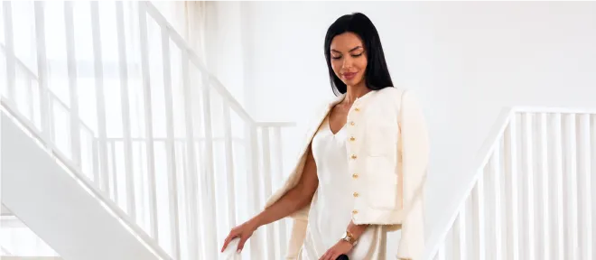 A woman in a cream jacket and satin skirt on a staircase