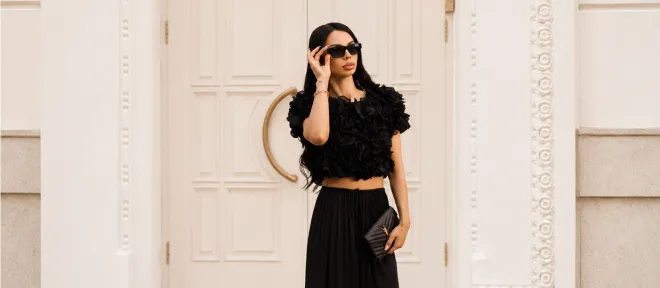 A woman in a black evening look by a carved door