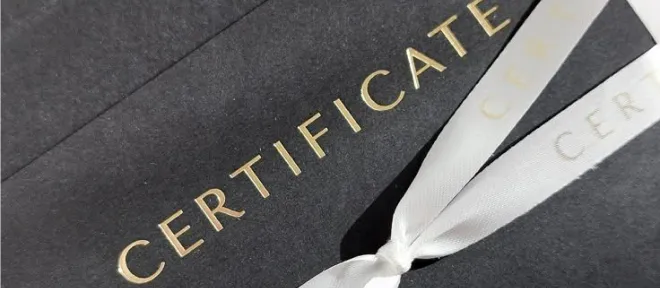 A black gift certificate envelope tied with a white satin ribbon