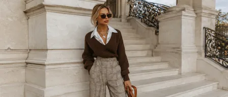 A woman in a brown jumper and checked trousers on marble steps