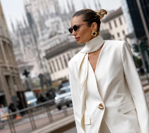 A woman in a white jacket and sunglasses on a city street