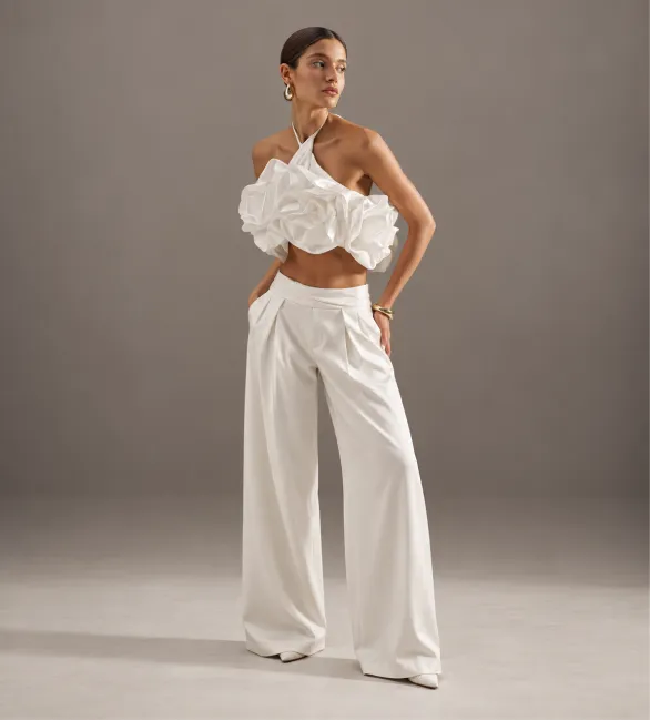 A white top with a voluminous flower and wide-leg trousers