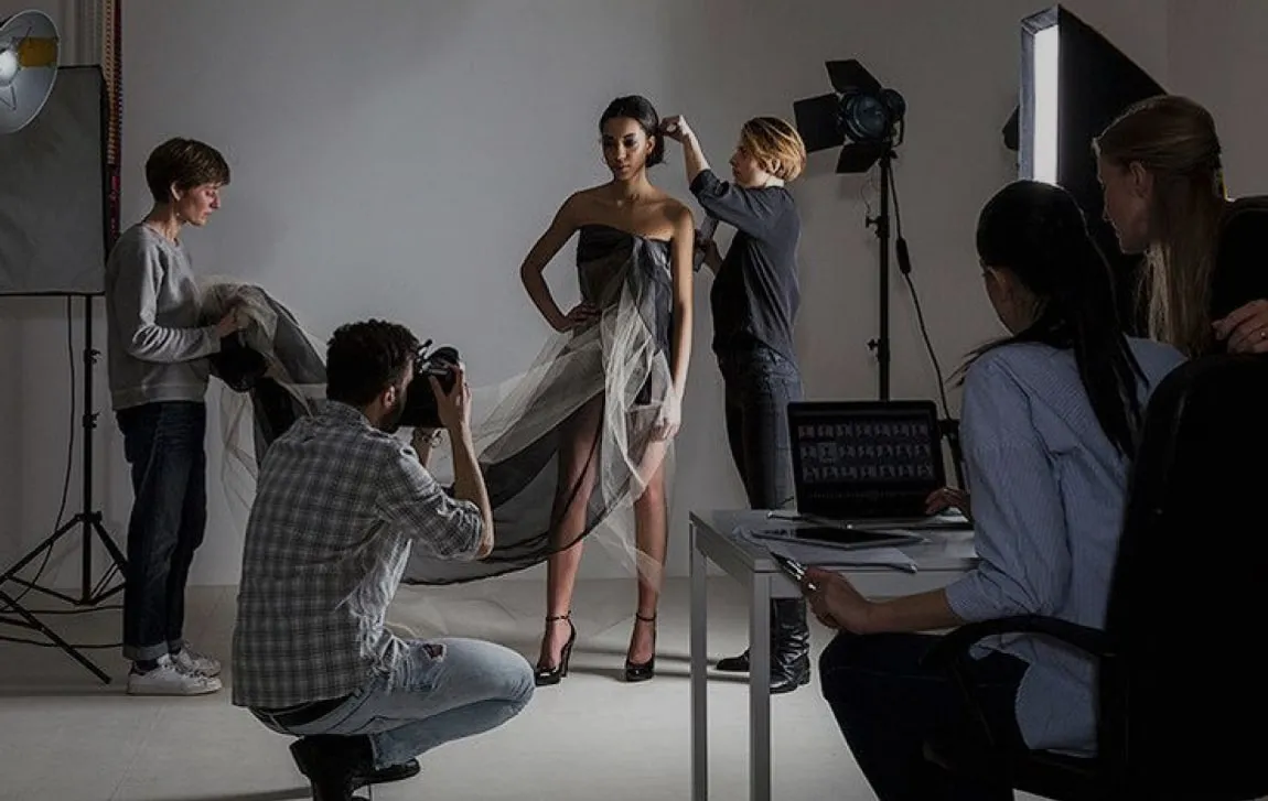 A fashion shoot in progress: a model on set with a photographer and the crew